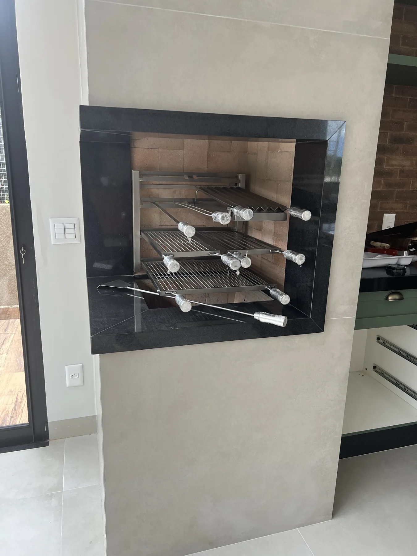 Grill Ossoboca instalado em churrasqueira residencial com moldura de granito preto