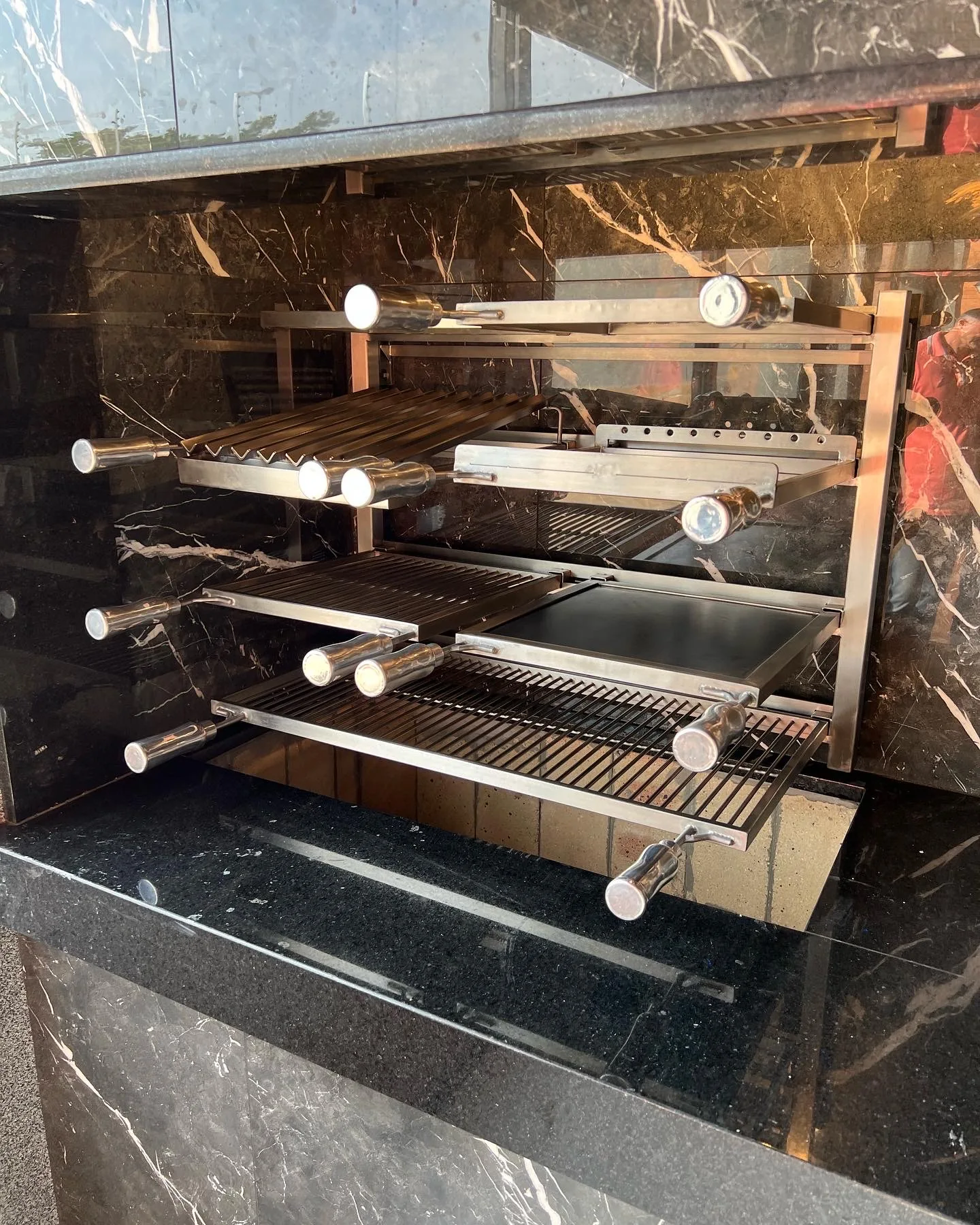 Grill Ossoboca com grelhas reguláveis instalado em churrasqueira de mármore preto